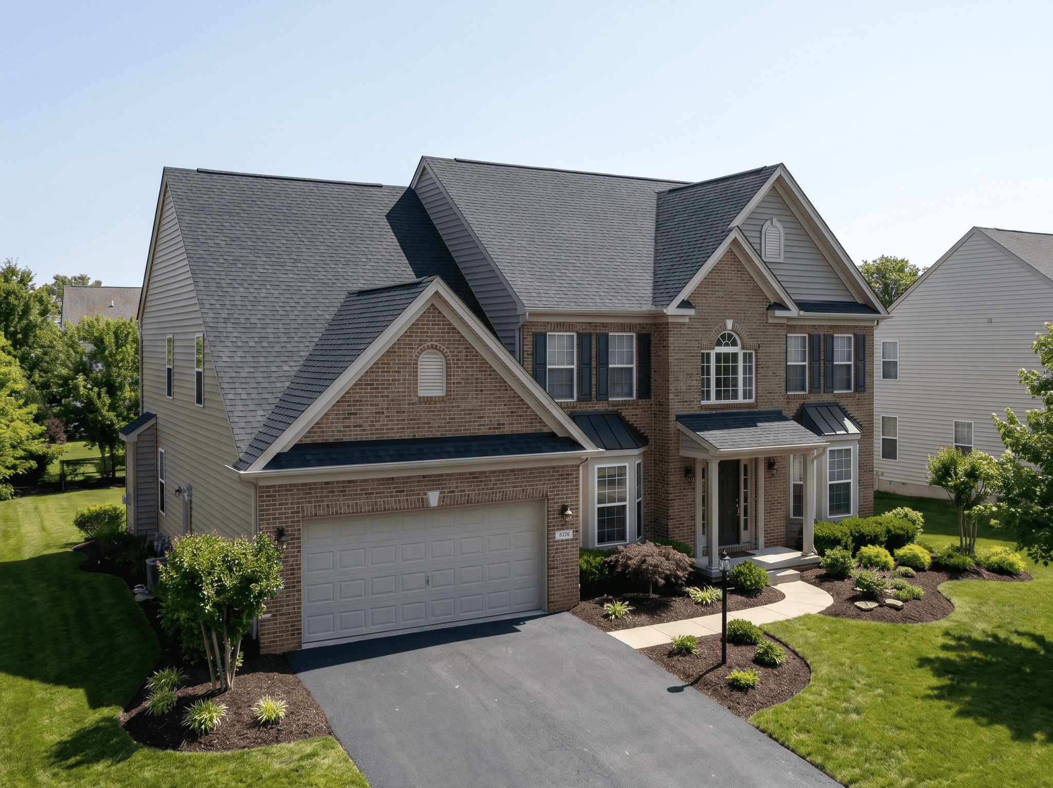 Beautiful brick and siding home with a well-maintained lawn and landscaping. Perfect example of resi.