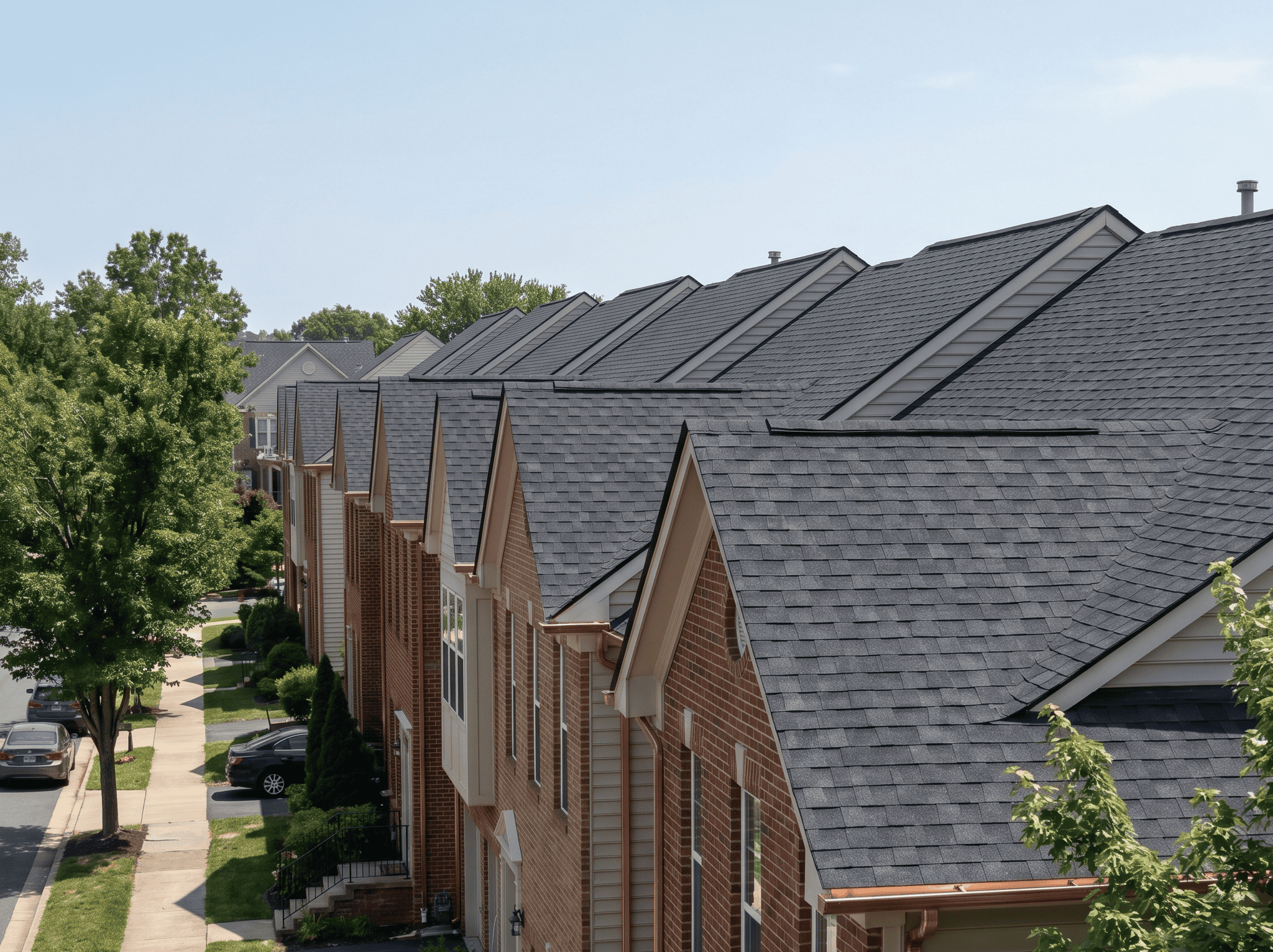 Townhouses with new asphalt shingle roofs in a residential neighborhood.