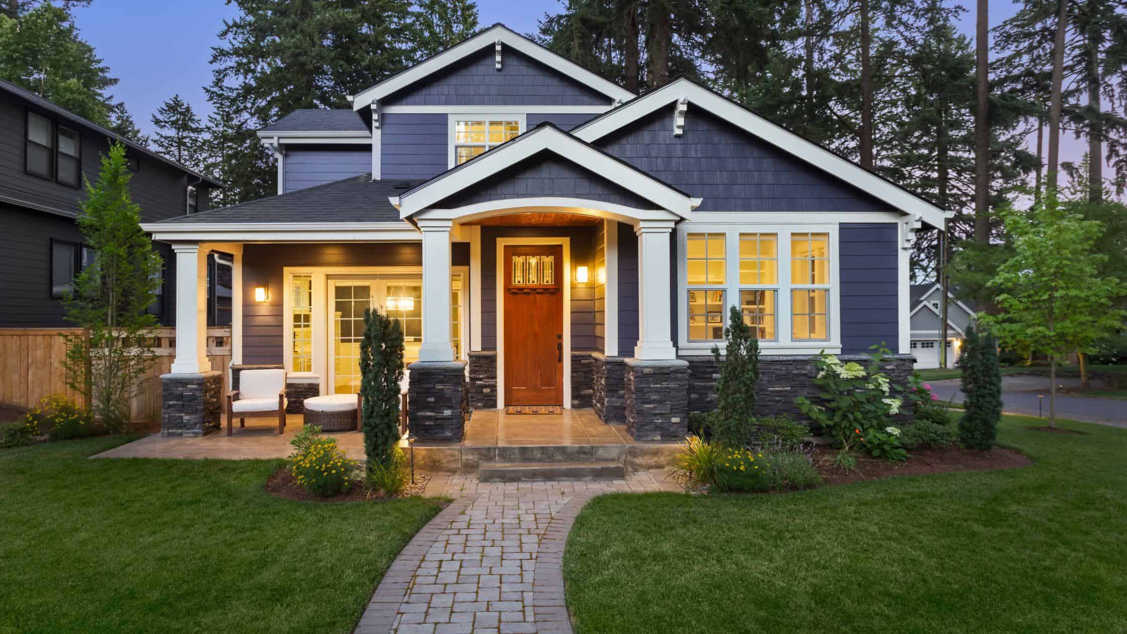Blue house exterior with front porch and landscaped yard.