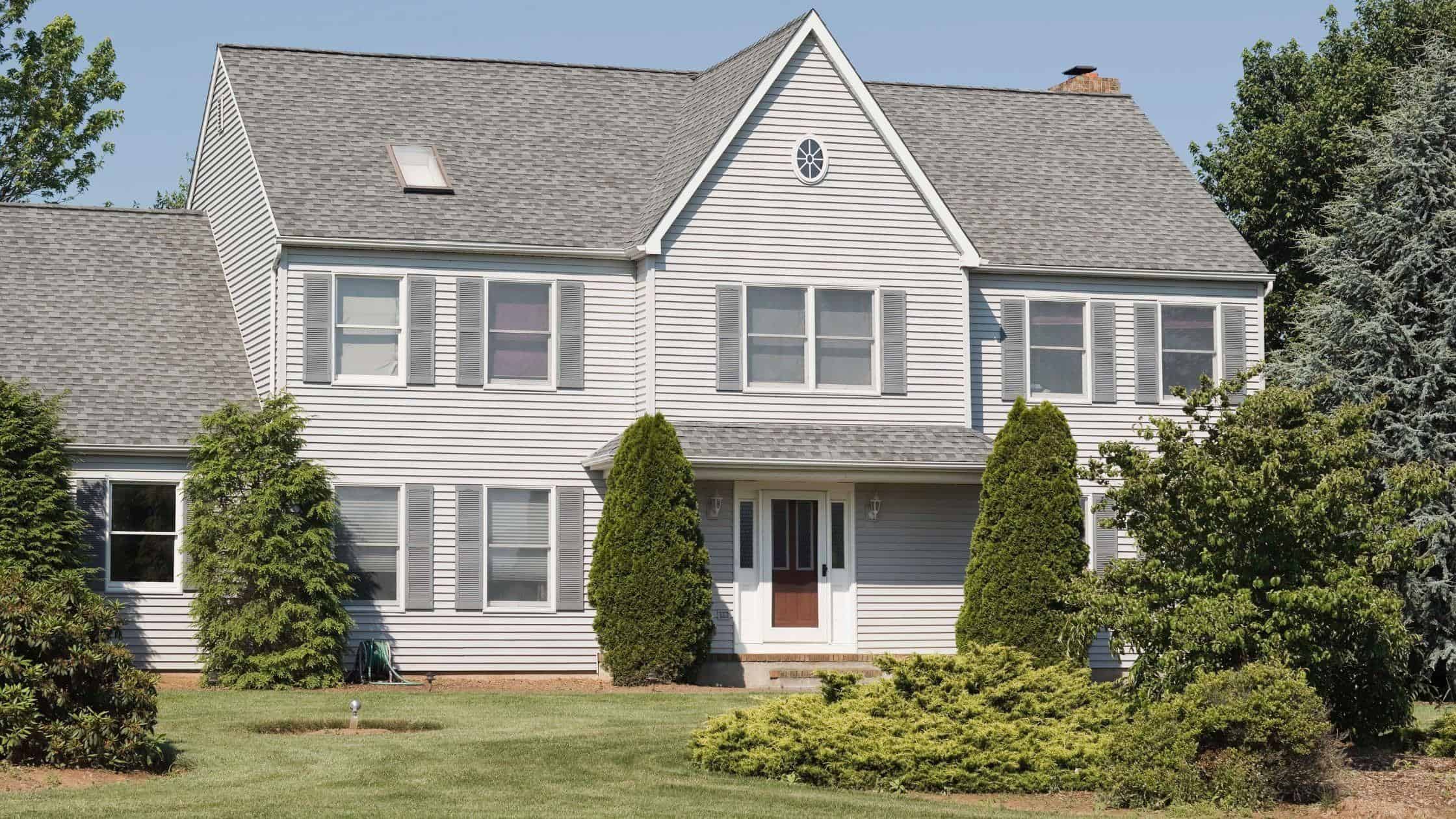 Modern Residential Home Beautiful white two-story house with well-maintained lawn and lush greenery, showcasing quality reno.