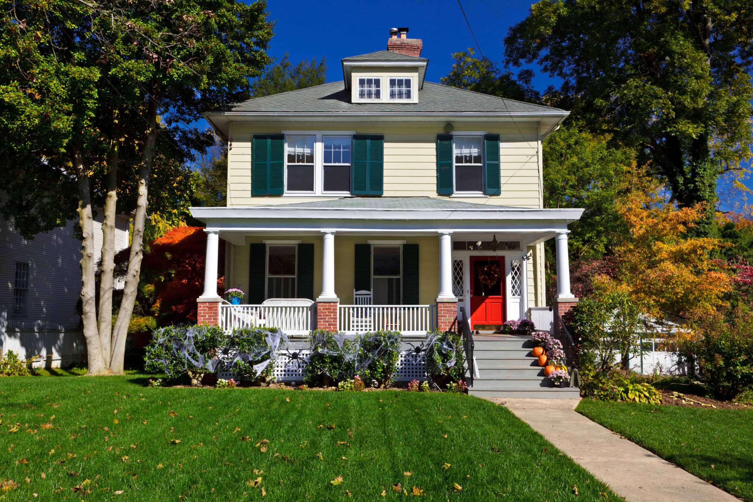 Colorful house with green shutters, red door, and well-maintained garden.